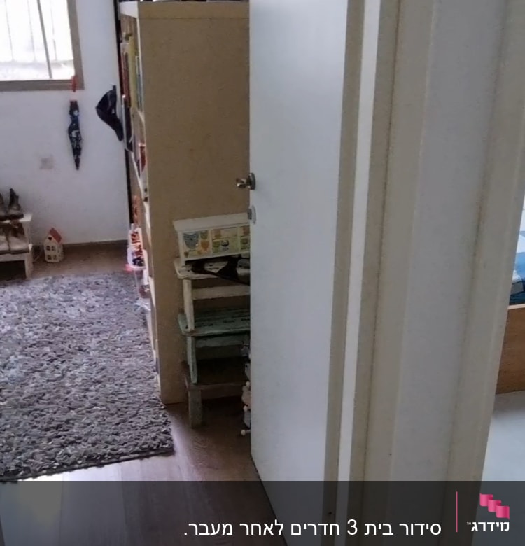 חדר ילדים עם מדף צעצועים ודלת פתוחה